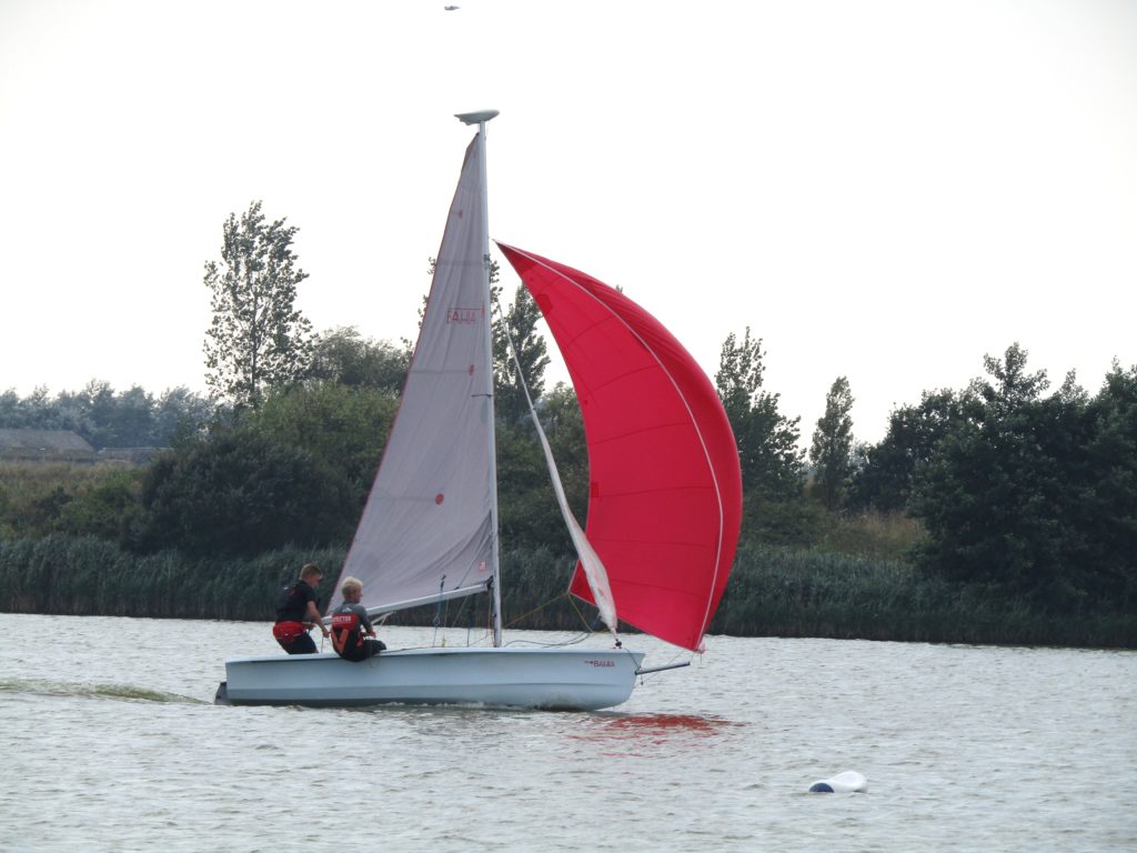 men sailing in dinghy with spinnaker