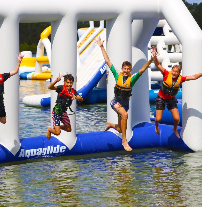 children jumping into the water from the aquapark at rye watersports in east sussex