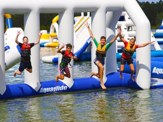 children jumping off aquapark inflatable into the lake at rye watersports